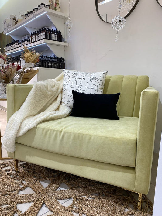 Sillón Mila de pana Velutti lima visto de frente, con almohadones y manta decorativos (no incluidos)