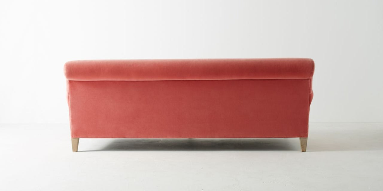 Sofá Cecily tapizado en velvet coral, vista posterior mostrando las patas traseras de madera - Tienda de Banquitos