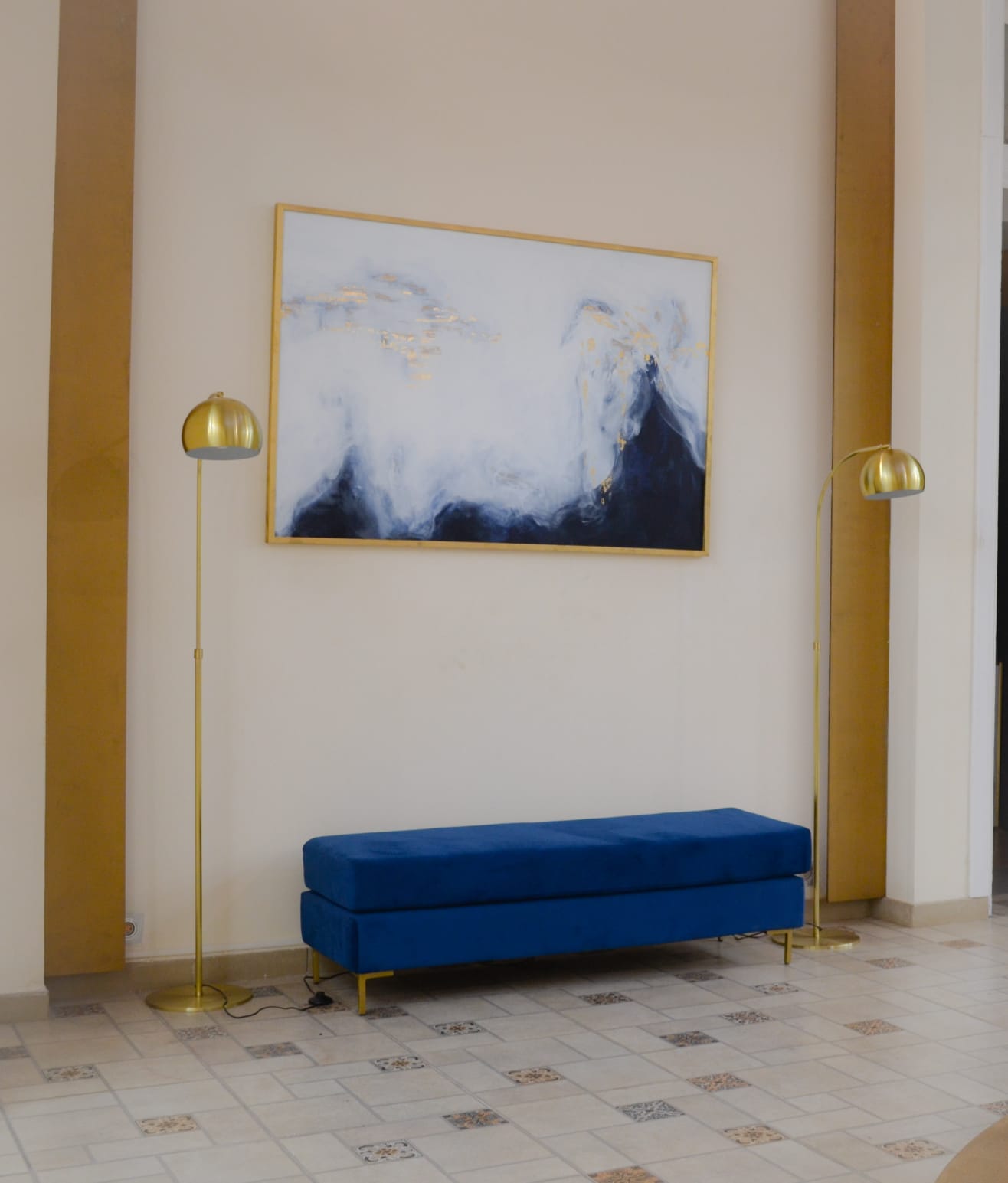 Banqueta de diseño moderno tapizada en azul con patas metálicas doradas. Ideal para pie de cama, recibidores o livings.