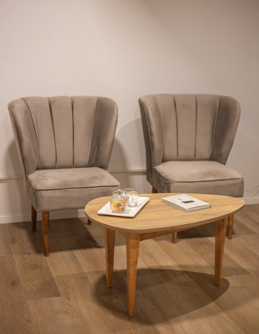 Dos butacas tapizadas en tela beige con respaldo alto y diseño con costuras verticales, apoyadas sobre patas de madera clara