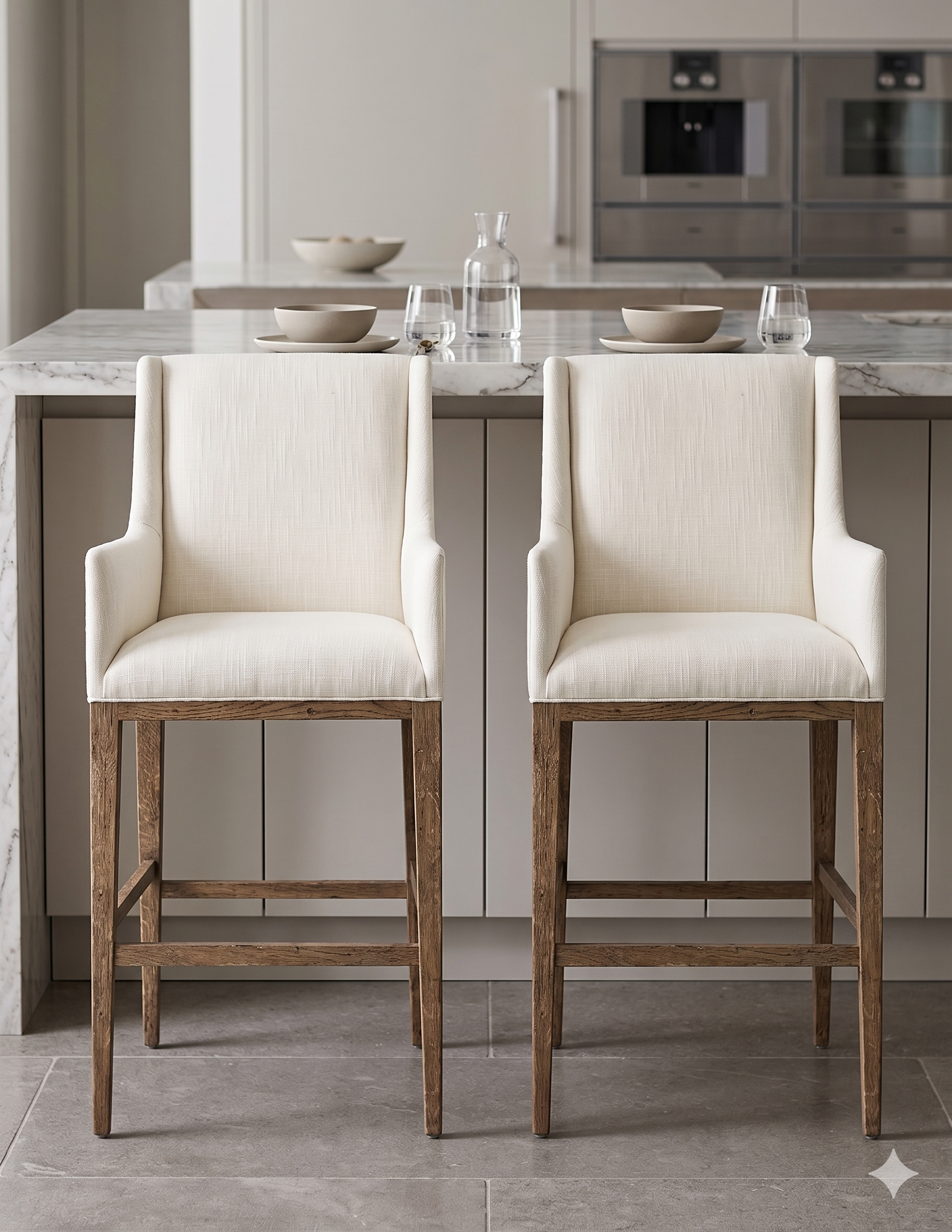 Banqueta alta de diseño contemporáneo con estructura de madera maciza en acabado natural. Presenta un asiento y respaldo integrado, tapizado en pana color claro con textura sutil. Incluye apoyapiés perimetral de madera para mayor estabilidad y confort