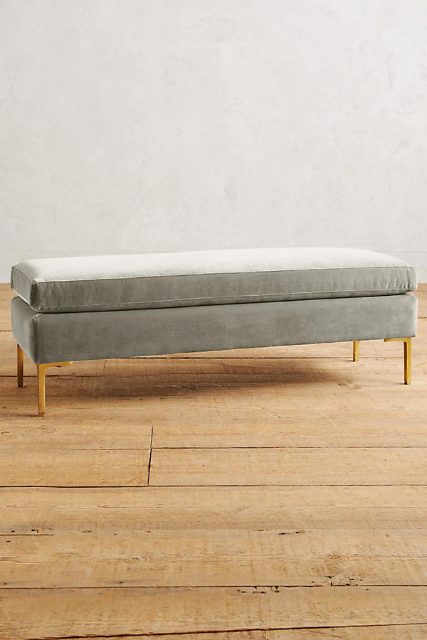 Banqueta de diseño moderno tapizada en  crema con patas metálicas doradas. Ideal para pie de cama, recibidores o livings.