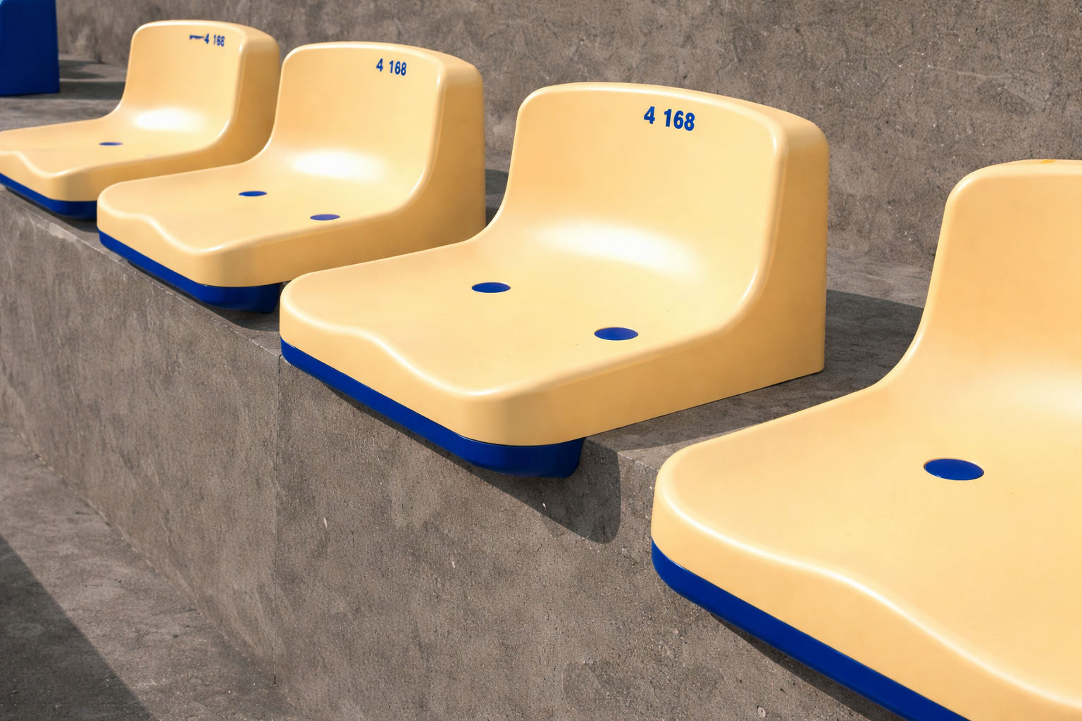Butaca de estadio plástica ergonómica instalada en gradas de hormigón, resistente a uso intensivo y condiciones exteriores.