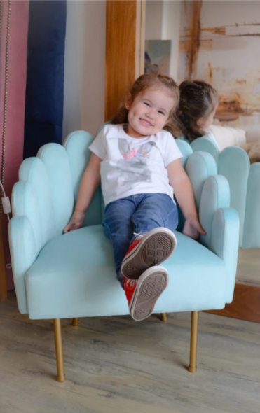 Sillón matero Mini Angie tapizado con respaldo y apoyabrazos de diseño ondulado y patas metálicas doradas.