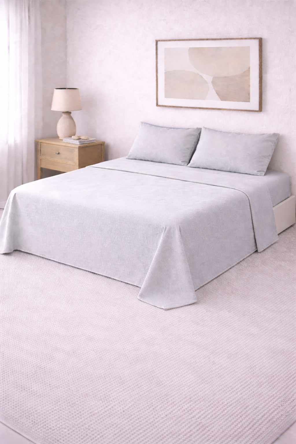 Cama de dos plazas con sábanas lisas en tono suave, prolijamente presentada en un ambiente cálido y minimalista con detalles en madera y decoración neutra.