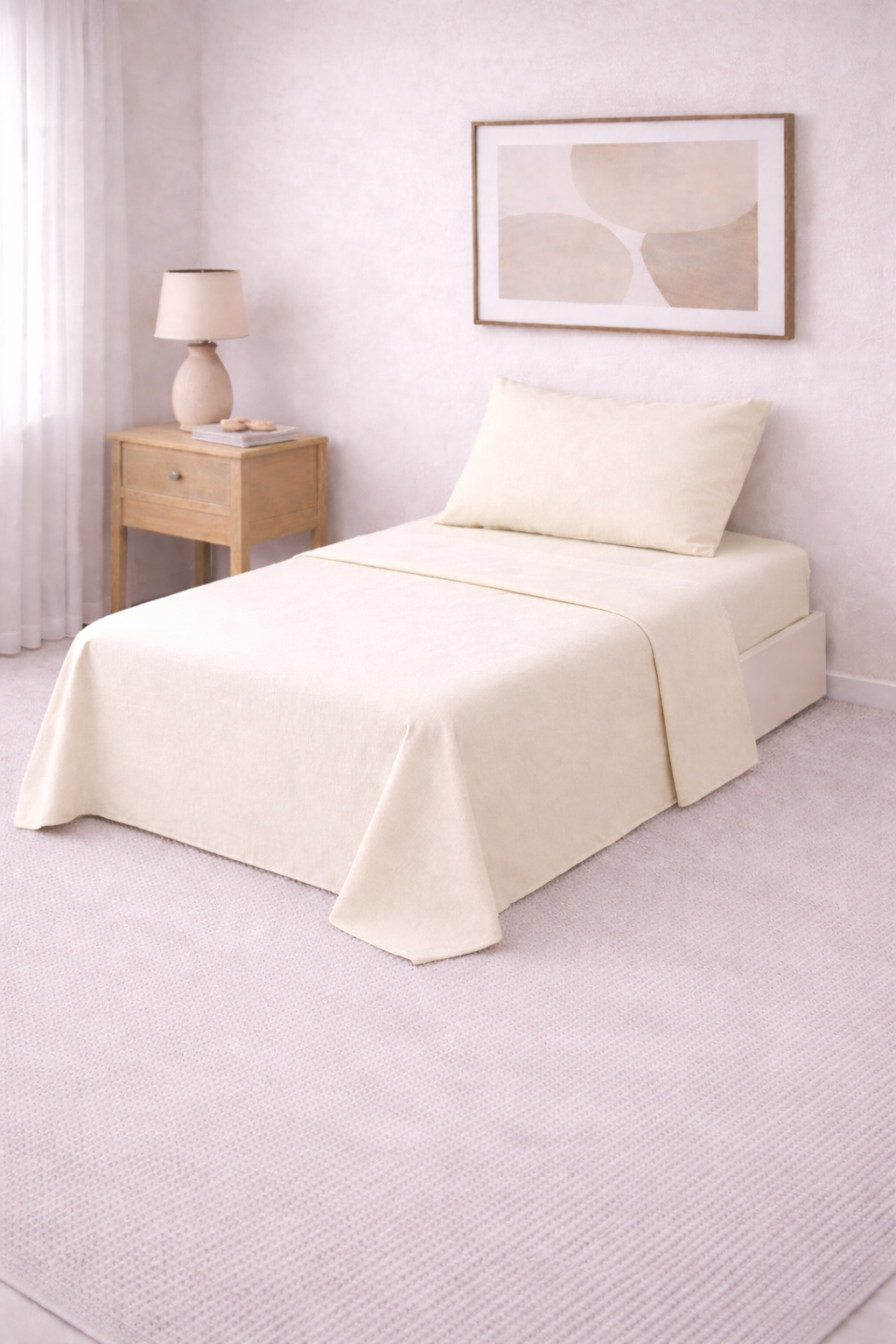 Cama de una plaza con sábanas lisas en tono suave, perfectamente tendida en un dormitorio luminoso de estilo minimalista con mesa de luz de madera y decoración neutra.