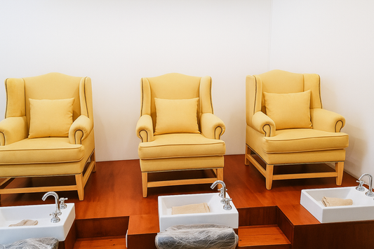 Conjunto de tres sillones altos de respaldo capitoné en color amarillo mostaza, colocados en fila sobre una tarima de madera. Cada uno cuenta con un almohadón a juego que refuerza la comodidad y aporta un aire estético y acogedor al espacio