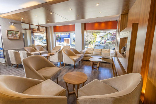 Salón del Hotel Carlos V en Bariloche ambientado con silloncitos París tapizados en tono neutro, dispuestos en forma circular con mesas de apoyo de madera.