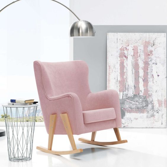 Mecedora tapizada en pana rosa con respaldo alto y base de madera curva.
