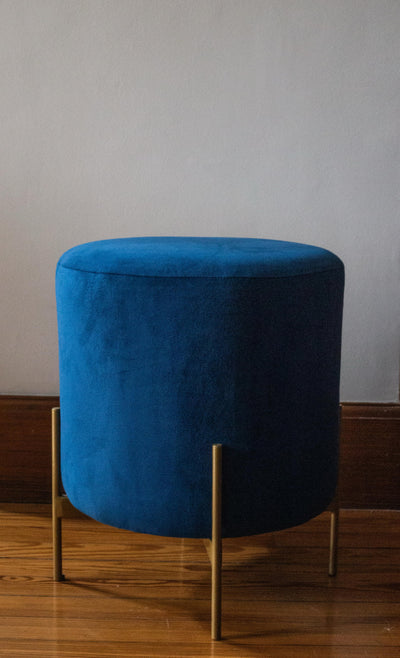 Puff redondo tapizado con patas metálicas doradas. Diseño moderno y sofisticado, ideal como acento decorativo en cualquier ambiente.