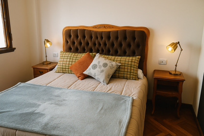 Cama con cabecera de madera curvada y tapizado capitoné en tono marrón, mostrando un diseño elegante y detallado que destaca sobre el resto del mobiliario de la habitación