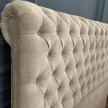 Respaldo de cama modelo Chesterfield con capitoné artesanal y botones, tapizado en tela suave, estilo clásico y elegante para realzar cualquier dormitorio.

