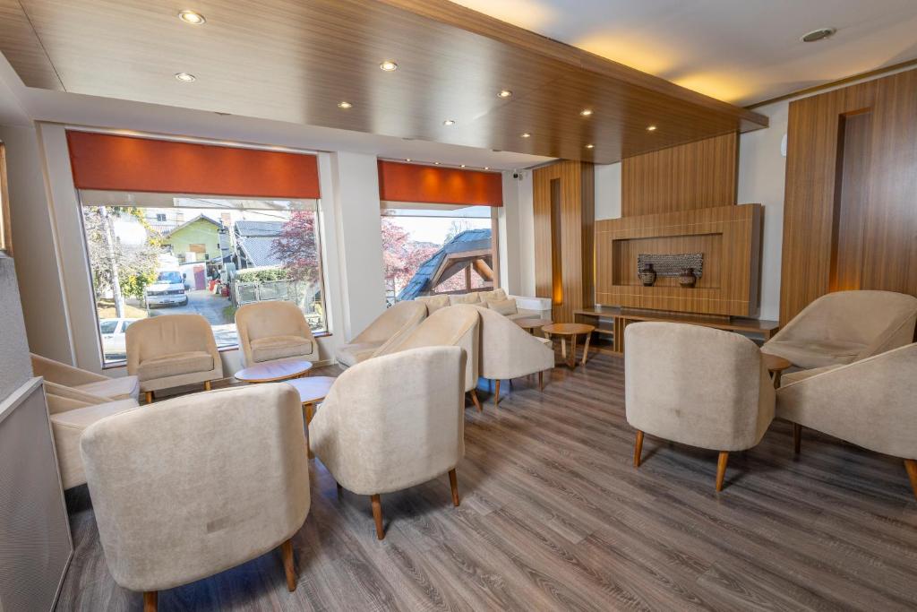Salón del Hotel Carlos V en Bariloche ambientado con silloncitos París tapizados en tono neutro, dispuestos en forma circular con mesas de apoyo de madera.