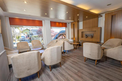 Salón del Hotel Carlos V en Bariloche ambientado con silloncitos París tapizados en tono neutro, dispuestos en forma circular con mesas de apoyo de madera.