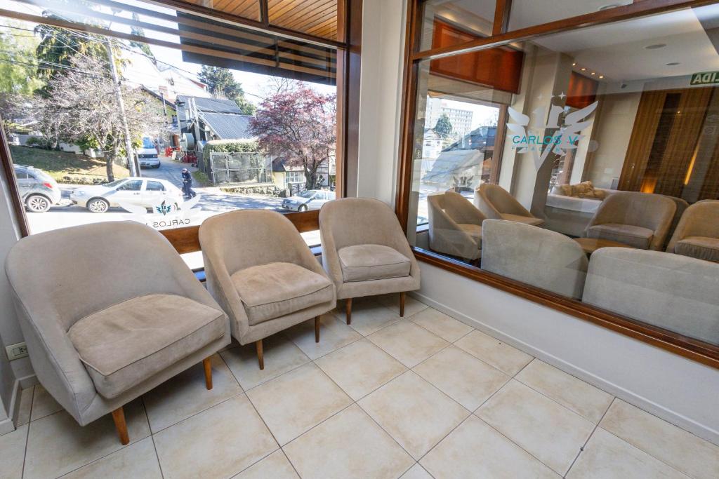 Salón del Hotel Carlos V en Bariloche ambientado con silloncitos París tapizados en tono neutro, dispuestos en forma circular con mesas de apoyo de madera.