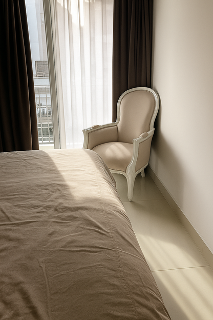 Un sillón individual estilo clásico francés, tapizado en pana color crema con estructura de madera tallada blanca, que combina distinción y comodidad en la decoración