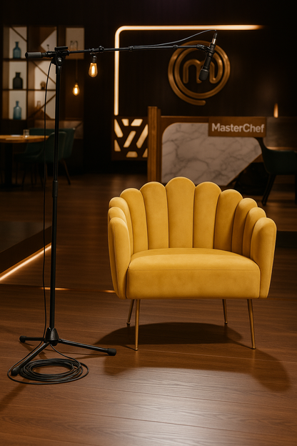 Sillón individual de diseño moderno con respaldo y brazos en forma de concha o pétalos, tapizado en terciopelo amarillo mostaza. Las patas delgadas de metal en acabado dorado complementan su estilo elegante y contemporáneo
