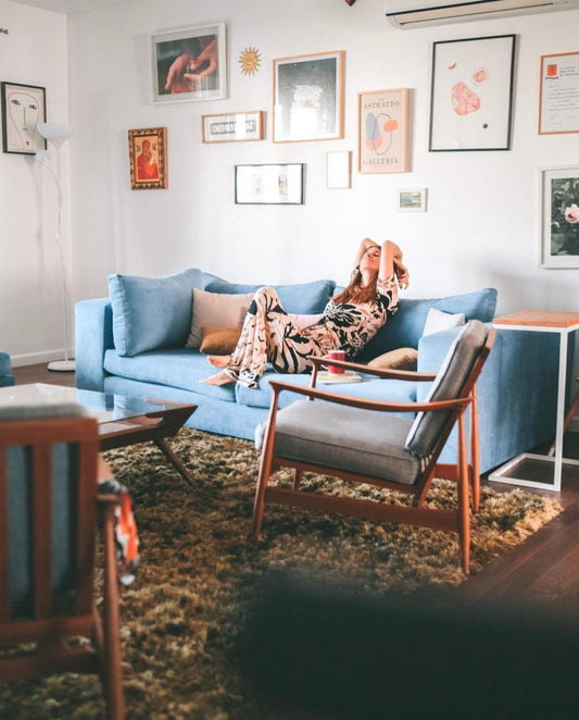 Un sillón esquinero en pana azul, acompañado de almohadones en tonos beige y rosados, que aportan contraste y calidez en un living de estilo moderno y acogedor