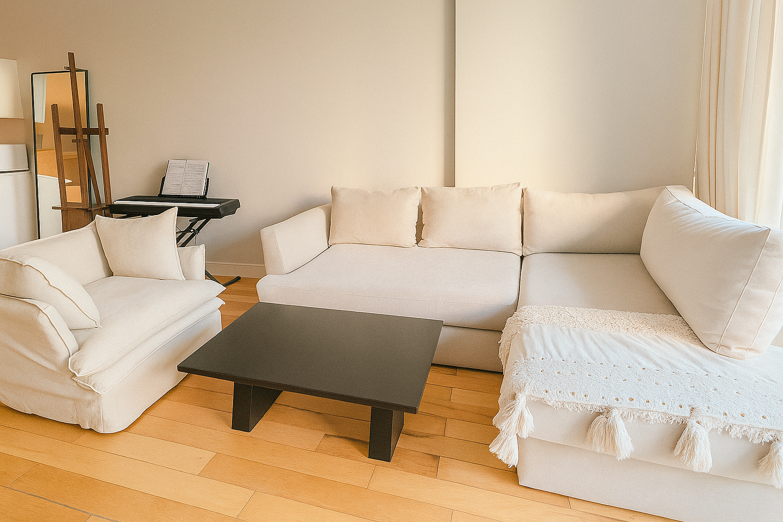 Living luminoso con mesa ratona rectangular negra, sofá esquinero beige y sillón de un cuerpo a juego, frente a un ventanal corredizo.