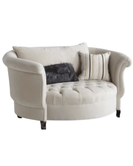Sillón redondo de estilo elegante en color gris, con respaldo curvo envolvente, apoyabrazos enrollados y asiento capitoné, patas cortas de madera.