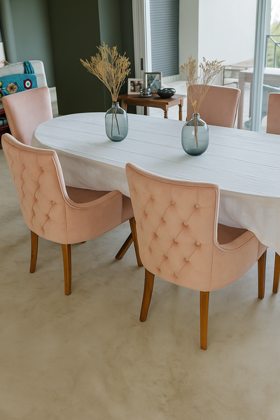 Silla de comedor con diseño capitoné en respaldo, tapizada en terciopelo rosa empolvado y patas de madera clara. Su estilo elegante y contemporáneo combina suavidad en la textura con un aire sofisticado, convirtiéndola en la pieza protagonista del ambiente.