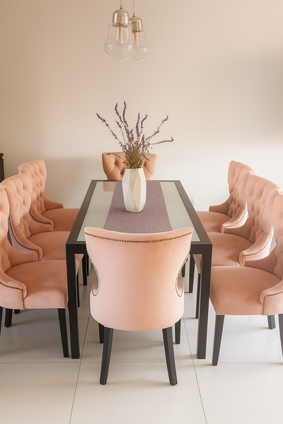 Juego de comedor moderno con mesa rectangular negra de tapa de vidrio y ocho sillas tapizadas en terciopelo rosa pastel, con respaldo capitoné y patas negras