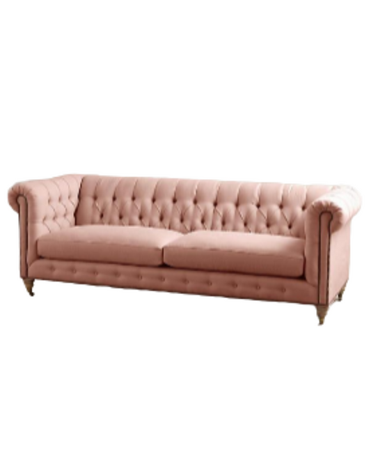 Sofá clásico Chesterfield, tapizado en pana, con respaldo y apoyabrazos capitoné, líneas elegantes y sofisticadas, patas de madera oscura tallada, sobre fondo blanco, ideal para decorar livings, oficinas o salas de estilo tradicional con un toque de lujo.