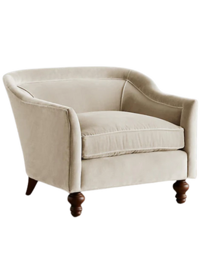 Sillón individual tapizado en color beige claro, con diseño de respaldo envolvente, asiento amplio y patas torneadas de madera oscura.