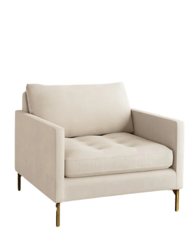 Sillón individual moderno en color crema con respaldo y asiento acolchados, apoyabrazos rectos y patas metálicas finas en dorado, sobre fondo blanco.
