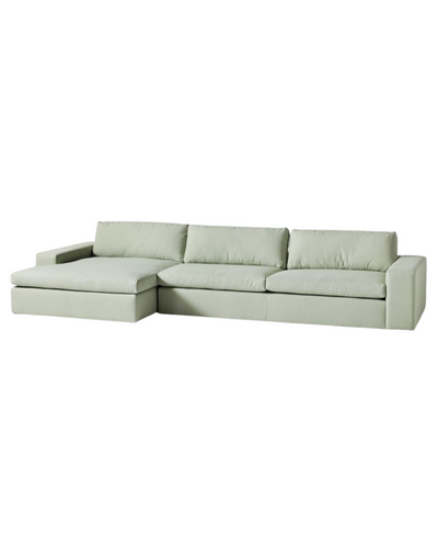 Sillón esquinero tapizado en gris, diseño lineal con base baja y almohadones grandes. Estética minimalista y fresca.