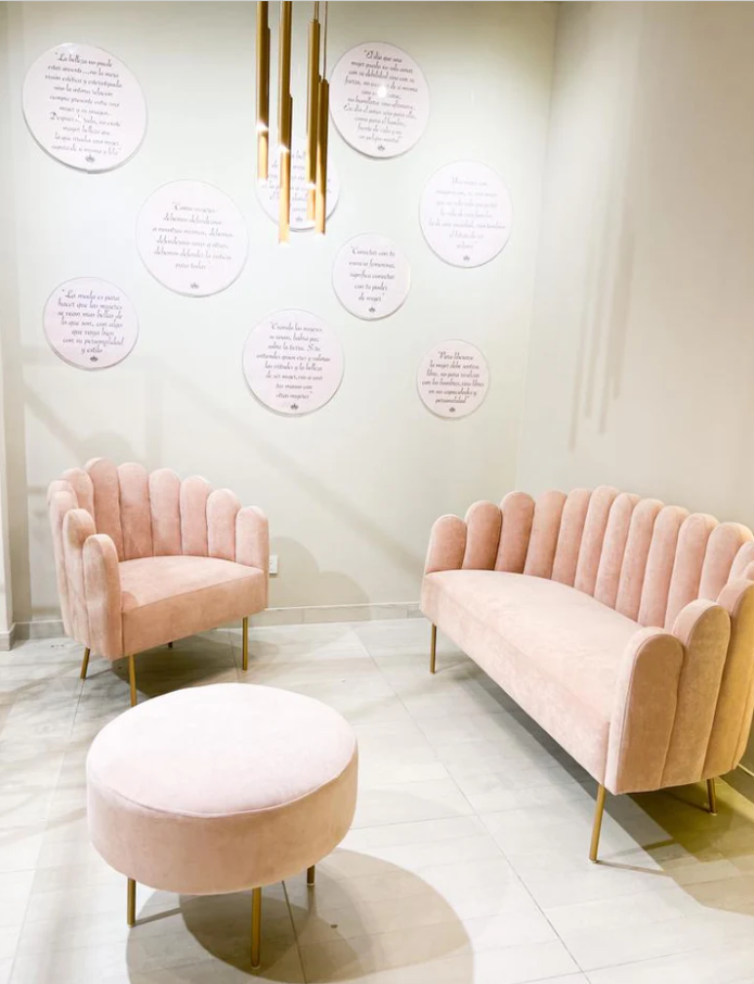 Sofá glam modelo Angie, con respaldo y apoyabrazos curvos en forma de concha, tapizado en pana, patas metálicas doradas delgadas y diseño compacto, sobre fondo blanco, ideal para salas de estar, dormitorios o rincones de lectura que buscan estilo y distinción.