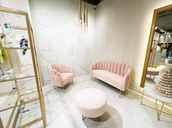 Sofá glam modelo Angie, con respaldo y apoyabrazos curvos en forma de concha, tapizado en pana, patas metálicas doradas delgadas y diseño compacto, sobre fondo blanco, ideal para salas de estar, dormitorios o rincones de lectura que buscan estilo y distinción.