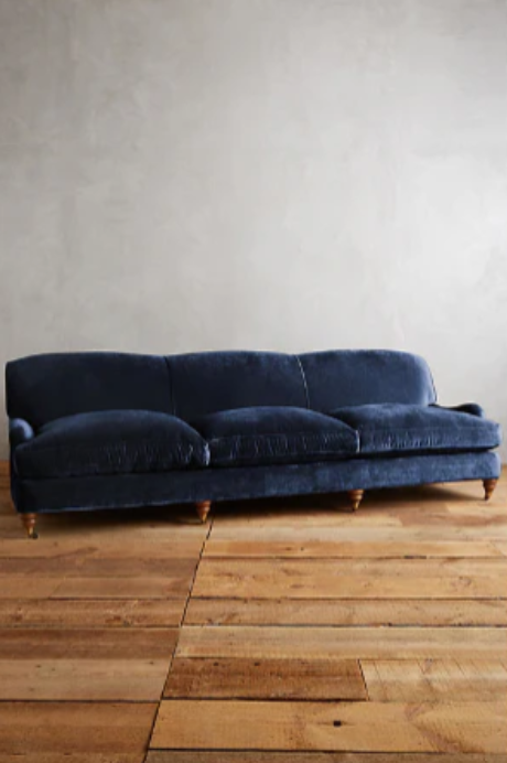 Sofá moderno modelo Minerva, tapizado con respaldo bajo y cojines de gran tamaño, estructura de líneas limpias y patas de madera clara, sobre fondo blanco, perfecto para ambientes minimalistas o espacios amplios y contemporáneos que buscan un toque de sofisticación.