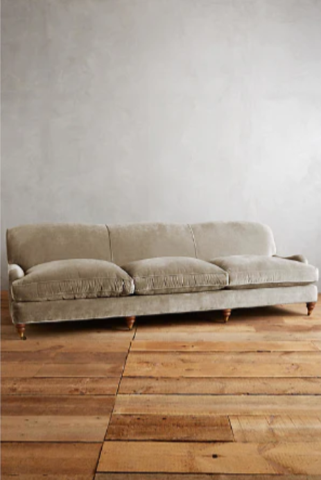 Sofá moderno modelo Minerva, tapizado con respaldo bajo y cojines de gran tamaño, estructura de líneas limpias y patas de madera clara, sobre fondo blanco, perfecto para ambientes minimalistas o espacios amplios y contemporáneos que buscan un toque de sofisticación.