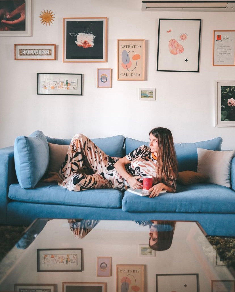 Un sillón esquinero en pana azul, acompañado de almohadones en tonos beige y rosados, que aportan contraste y calidez en un living de estilo moderno y acogedor