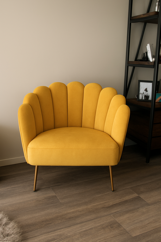 illón individual de diseño moderno con respaldo en forma de concha o pétalos, tapizado en terciopelo amarillo mostaza. Sus patas delgadas de metal en acabado dorado complementan el estilo elegante y contemporáneo de la pieza.