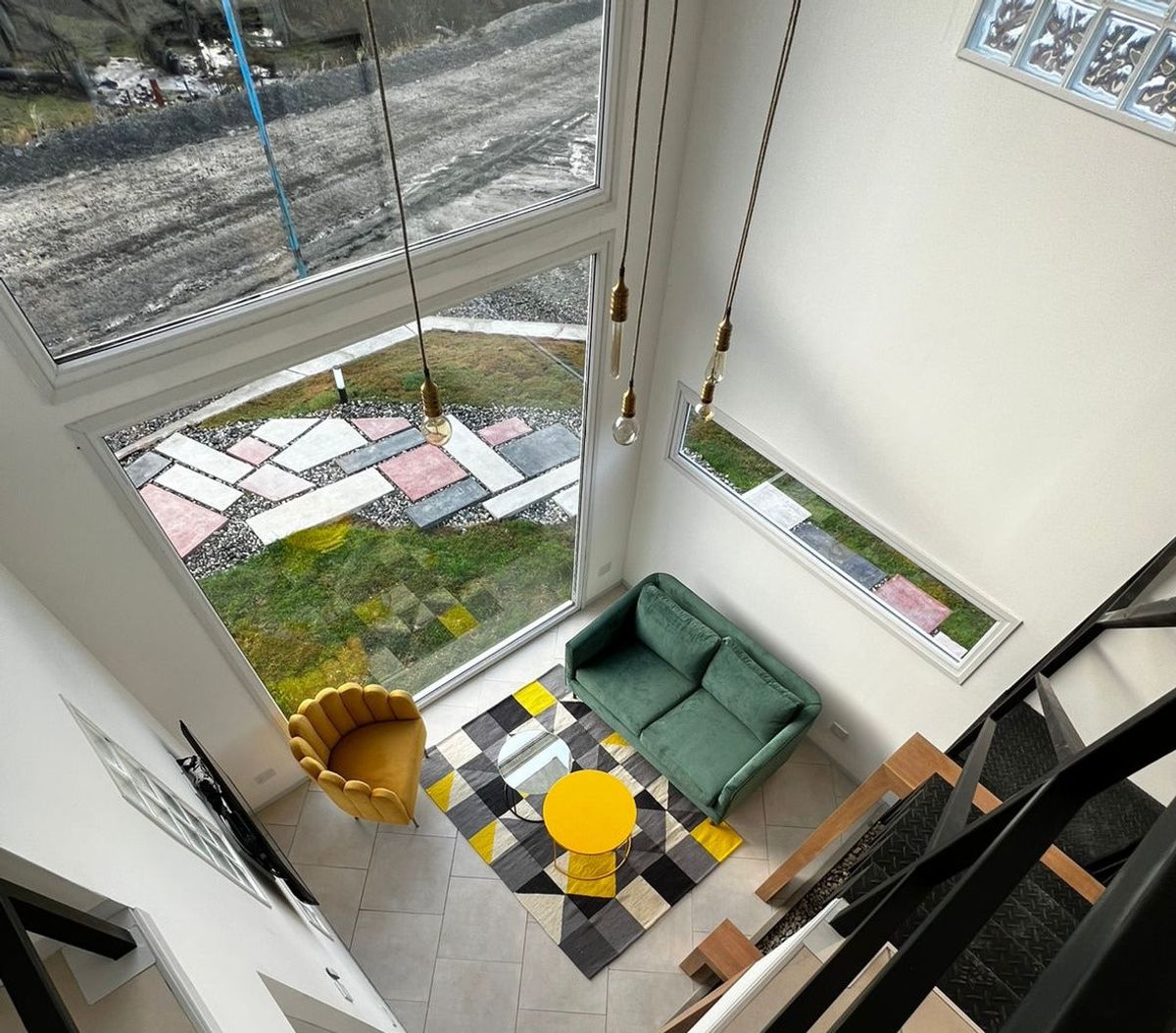 Vista desde el entrepiso del loft de Austral Rental en Ushuaia: Sofá Corina verde, Sillón Angie mostaza y mesa ratona amarilla