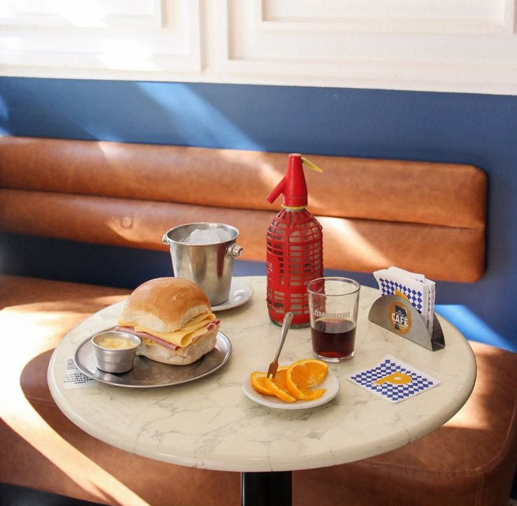 Banco corrido en tono suela con zócalo azul, detrás de una mesa de mármol servida en Café Polvorín