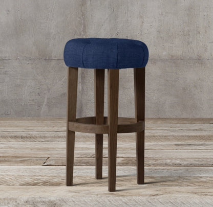 Banqueta Alta Barista en azul con asiento redondo capitoné y patas de madera oscura