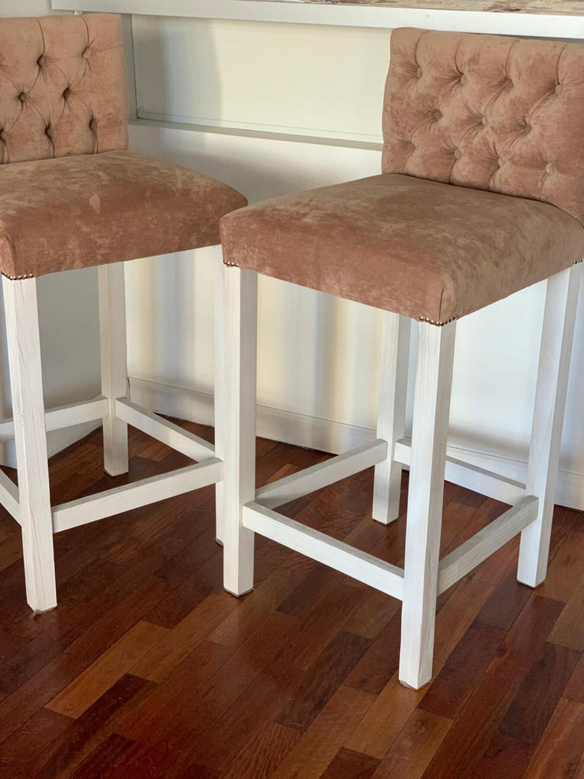 Dos Banquetas altas Venet en beige con respaldo capitoné, tachas en el asiento y patas de madera blancas envejecidas, en la cocina de Camila