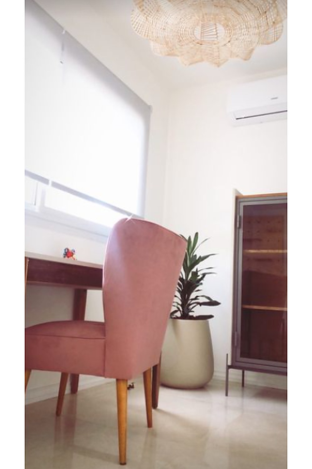 Sillón Matero Alpes rosa terracota de perfil, frente a un escritorio y una vitrina de hierro