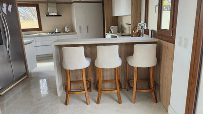 Cocina de la casa de Dani en Puerto Madryn con tres Banquetas Altas Simón en crema con patas de madera