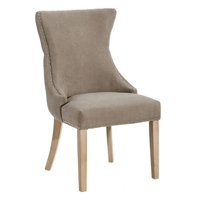Silla Charis tapizada en gris topo vista de frente, con tachas en el borde y patas de madera