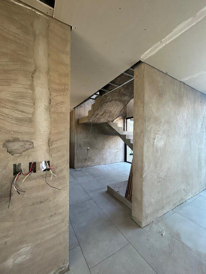 Interior del Club House del Country Área 60 en obra, con muros de hormigón y la escalera al fondo