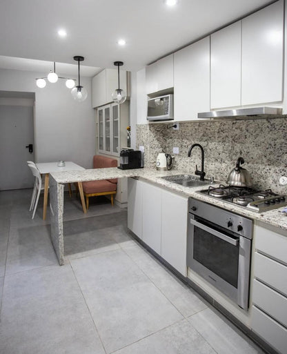Cocina integrada con muebles blancos y mesada de granito, con el banco terracota a medida al fondo, junto a WN Interiores