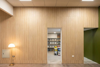 Detalle del revestimiento de madera clara con las puertas de servicio integradas en las oficinas del Banco del Chaco