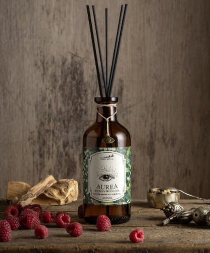Difusor de varillas Aurea de Petite Affaire con varillas negras, palo santo y frambuesas sobre madera