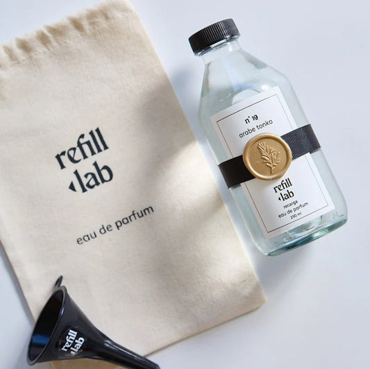Recarga de 250 ml de Árabe Tonka Refill Lab junto a su bolsa de tela y un embudo negro