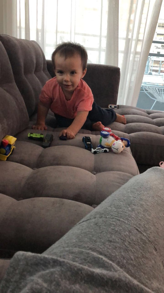 Bebé jugando sobre el asiento capitoné del Sillón Esquinero Bambú gris, en el departamento de Antonella en Belgrano
