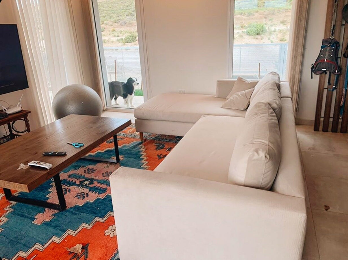 Esquinero Bélgica blanco en L frente al ventanal con vista a la sierra, en la casa de campo de Mariana